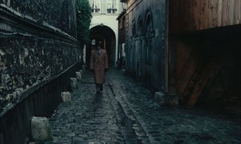 Movie still from “Mr. Klein” (1976), directed by Joseph Losey – A man walking down the street in a trench coat; Wide shot, High angle