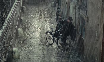 Movie still from “Mr. Klein” (1976), directed by Joseph Losey – A man with a bicycle in the middle of a street; Extreme Wide shot, High angle