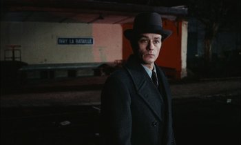 Movie still from “Mr. Klein” (1976), directed by Joseph Losey – A man wearing a black hat and a black coat; Medium shot, Over the shoulder angle