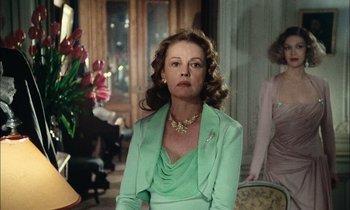 Movie still from “Mr. Klein” (1976), directed by Joseph Losey – A woman in a green dress in a living room; Medium shot, Over the shoulder angle