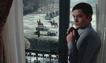 Movie still from “Mr. Klein” (1976), directed by Joseph Losey – A man standing in front of an open window with horses in the background; Medium shot, Low angle