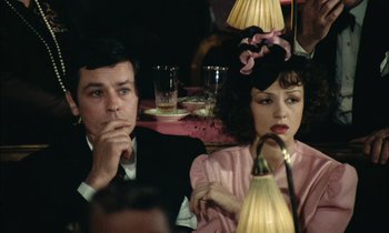 Movie still from “Mr. Klein” (1976), directed by Joseph Losey – A man and a woman sitting next to each other at a table; Close Up shot, Over the shoulder angle