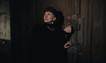 Movie still from “Mr. Klein” (1976), directed by Joseph Losey – An older woman standing in front of an open door; Medium shot, Low angle