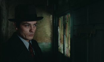 Movie still from “Mr. Klein” (1976), directed by Joseph Losey – A man wearing a suit and hat in a dark room; Close Up shot, Over the shoulder angle