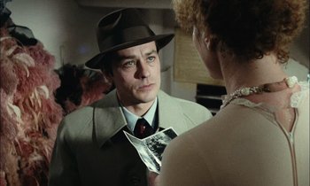 Movie still from “Mr. Klein” (1976), directed by Joseph Losey – A man wearing a hat and a tie talking to a woman in front of a mirror; Close Up shot, Over the shoulder angle