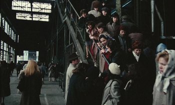 Movie still from “Mr. Klein” (1976), directed by Joseph Losey – A group of people standing next to a metal staircase; Wide shot, High angle