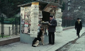 Movie still from “Mr. Klein” (1976), directed by Joseph Losey – A man standing next to a dog on the side of the street; Wide shot, High angle