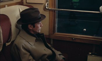 Movie still from “Mr. Klein” (1976), directed by Joseph Losey – A man sitting on a train looking out the window; Medium shot, High angle