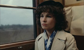 Movie still from “Mr. Klein” (1976), directed by Joseph Losey – A woman in a trench coat sitting on a train; Close Up shot, High angle