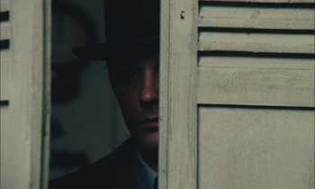 Movie still from “Mr. Klein” (1976), directed by Joseph Losey – A man in a suit and a hat looking out of a window; Close Up shot, Over the shoulder angle