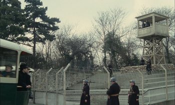 Movie still from “Mr. Klein” (1976), directed by Joseph Losey – A group of men standing next to each other near barbed wire; Extreme Wide shot, Low angle
