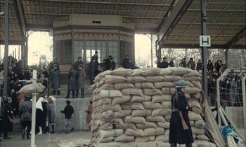 Movie still from “Mr. Klein” (1976), directed by Joseph Losey – A group of people standing next to a pile of sand bags; Extreme Wide shot, High angle