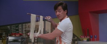 Movie still from “Mr. Nice Guy” (1997), directed by Sammo Kam-Bo Hung – A man in an orange and white apron using a knife to cut noodles; Medium shot, Low angle
