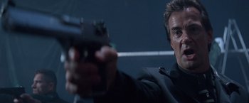 Movie still from “Mr. Nice Guy” (1997), directed by Sammo Kam-Bo Hung – A man holding a gun while standing next to a microphone; Close Up shot, Low angle