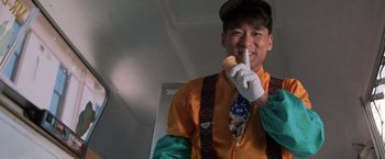 Movie still from “Mr. Nice Guy” (1997), directed by Sammo Kam-Bo Hung – A man wearing a hat and a tie while eating a sandwich; Close Up shot, Low angle