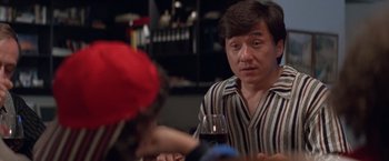 Movie still from “Mr. Nice Guy” (1997), directed by Sammo Kam-Bo Hung – A man sitting at a table holding a glass of wine; Close Up shot, Over the shoulder angle
