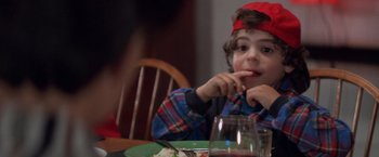 Movie still from “Mr. Nice Guy” (1997), directed by Sammo Kam-Bo Hung – A young boy sitting at a table eating a meal; Close Up shot, Over the shoulder angle