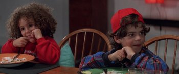 Movie still from “Mr. Nice Guy” (1997), directed by Sammo Kam-Bo Hung – A boy in a red hat is sitting at a table; Close Up shot, High angle