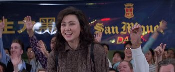 Movie still from “Mr. Nice Guy” (1997), directed by Sammo Kam-Bo Hung – A woman in a brown shirt is smiling for the camera; Medium shot, Low angle