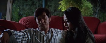Movie still from “Mr. Nice Guy” (1997), directed by Sammo Kam-Bo Hung – A man and a woman sitting on a red couch; Medium shot, Low angle