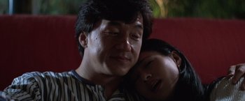 A man and a woman snuggling on a red couch