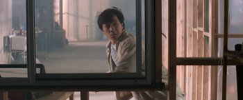 Movie still from “Mr. Nice Guy” (1997), directed by Sammo Kam-Bo Hung – A man looking out of a window in a building; Medium shot, Over the shoulder angle