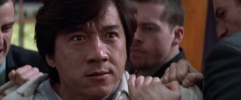 Movie still from “Mr. Nice Guy” (1997), directed by Sammo Kam-Bo Hung – A man standing next to another man in a room; Close Up shot, Over the shoulder angle