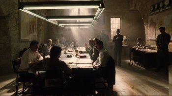 Movie still from “Munich” (2005), directed by Steven Spielberg – A group of people sitting at a table in a room; Wide shot, High angle