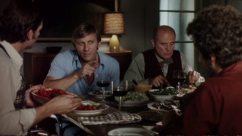 Movie still from “Munich” (2005), directed by Steven Spielberg – A group of people sitting at a dinner table; Medium shot, Over the shoulder angle