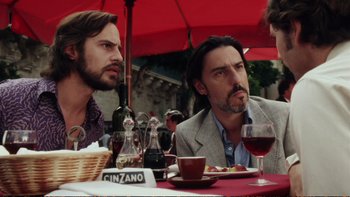 Movie still from “Munich” (2005), directed by Steven Spielberg – A couple of men sitting at a table with wine glasses; Medium shot, Over the shoulder angle