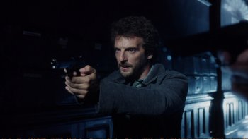 Movie still from “Munich” (2005), directed by Steven Spielberg – A man holding a gun in a dark room at night; Close Up shot, Low angle