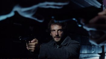 Movie still from “Munich” (2005), directed by Steven Spielberg – A man holding a gun in a dark room; Close Up shot, Low angle