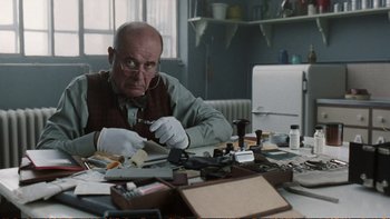 Movie still from “Munich” (2005), directed by Steven Spielberg – An older man sitting at a desk with a lot of papers; Close Up shot, Low angle