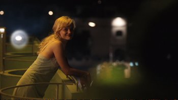 Movie still from “Munich” (2005), directed by Steven Spielberg – A beautiful blonde woman sitting on a railing; Medium shot, Low angle