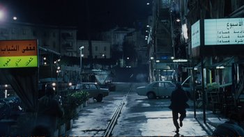 Movie still from “Munich” (2005), directed by Steven Spielberg – A person walking down a street at night; Extreme Wide shot, High angle
