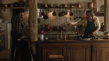 Movie still from “Munich” (2005), directed by Steven Spielberg – A person in a kitchen preparing a meal; Medium shot, Over the shoulder angle