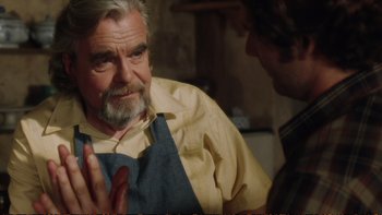 Movie still from “Munich” (2005), directed by Steven Spielberg – An older man wearing an apron talking to a younger man; Close Up shot, Over the shoulder angle