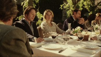 Movie still from “Munich” (2005), directed by Steven Spielberg – A group of people sitting at a table with wine glasses; Medium shot, Over the shoulder angle