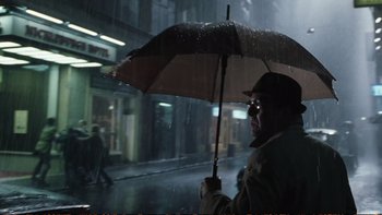 Movie still from “Munich” (2005), directed by Steven Spielberg – A man holding an umbrella while standing in the rain; Medium shot, Low angle