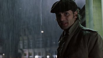 Movie still from “Munich” (2005), directed by Steven Spielberg – A man wearing a hat standing in the rain; Close Up shot, Low angle