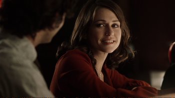 Movie still from “Munich” (2005), directed by Steven Spielberg – A beautiful woman in a red shirt sitting in front of a man; Close Up shot, Over the shoulder angle