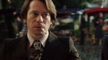 Movie still from “Munich” (2005), directed by Steven Spielberg – A person wearing a suit smoking a cigarette; Close Up shot, Over the shoulder angle