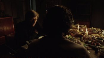 Movie still from “Munich” (2005), directed by Steven Spielberg – Two people sitting at a dinner table in the dark; Medium shot, Over the shoulder angle