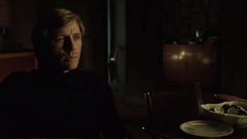 Movie still from “Munich” (2005), directed by Steven Spielberg – A man sitting at a table in a dark room; Close Up shot, Over the shoulder angle