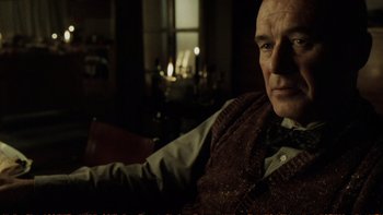 Movie still from “Munich” (2005), directed by Steven Spielberg – An older man sitting in front of a fireplace; Close Up shot, Over the shoulder angle