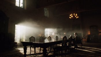 Movie still from “Munich” (2005), directed by Steven Spielberg – A group of people sitting at a table in a room; Extreme Wide shot, Low angle