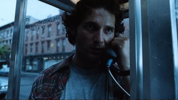 Movie still from “Munich” (2005), directed by Steven Spielberg – A man talking on a phone while standing on a bus; Close Up shot, Low angle