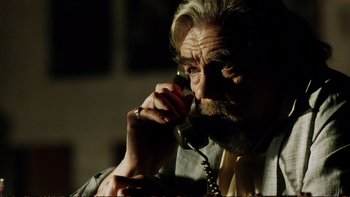 Movie still from “Munich” (2005), directed by Steven Spielberg – An older man talking on a phone while sitting down; Close Up shot, Low angle