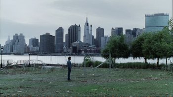 Movie still from “Munich” (2005), directed by Steven Spielberg – A man standing in a field with a city skyline in the background; Extreme Wide shot, Over the shoulder angle