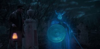 Movie still from “Muppets Haunted Mansion” (2021), directed by Kirk R. Thatcher – A person in a costume holding a shield in front of a fire hydrant; Medium shot, Low angle
